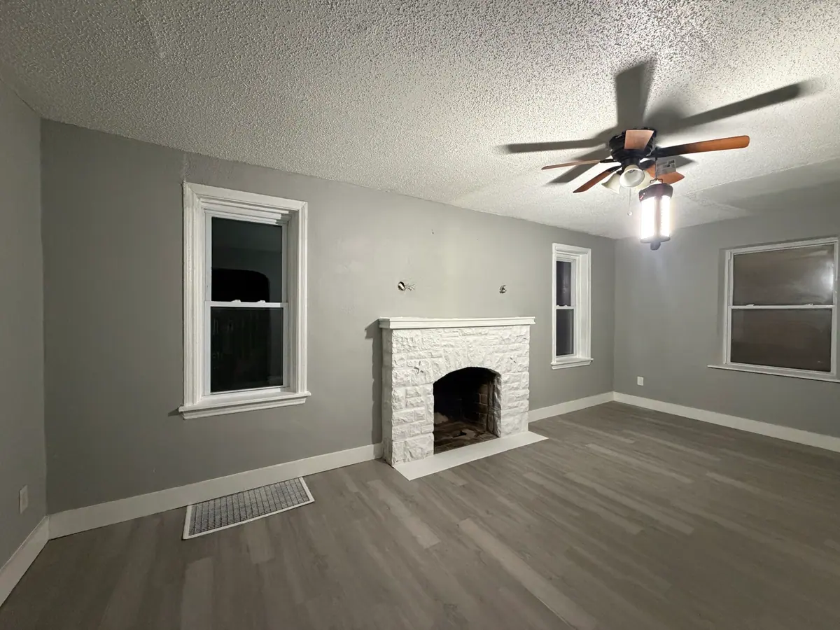 The same room finished: grey walls, white trim, the stone fireplace painted white and wide plank flooring run wall to wall